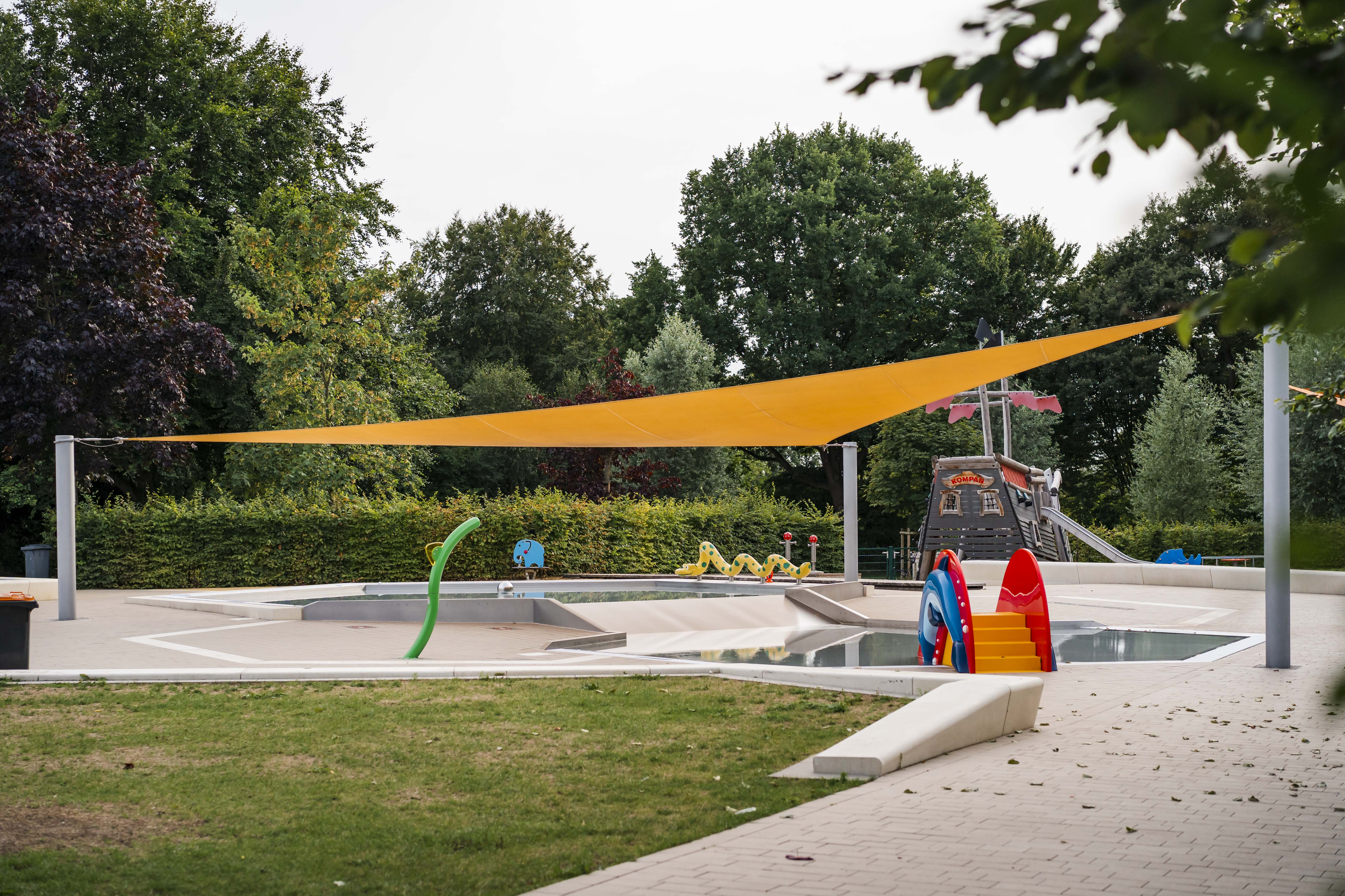 großes, oranges, dreieckiges Ganzjahressonnensegel über Pool im Freibad