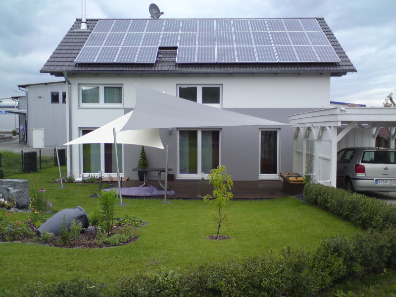Startseite Sonnensegel wasserdicht Zwei sich überlappende, dreieckige Sonnensegel im Garten in grau und weiß